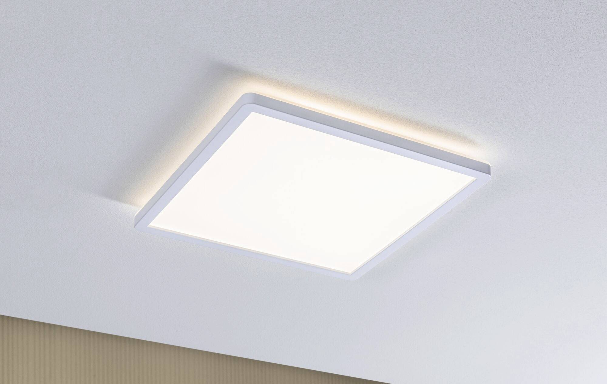 Biała, kwadratowa lampa sufitowa zamontowana na suficie, zapewniająca miękkie rozproszenie światła. Minimalistyczny design.