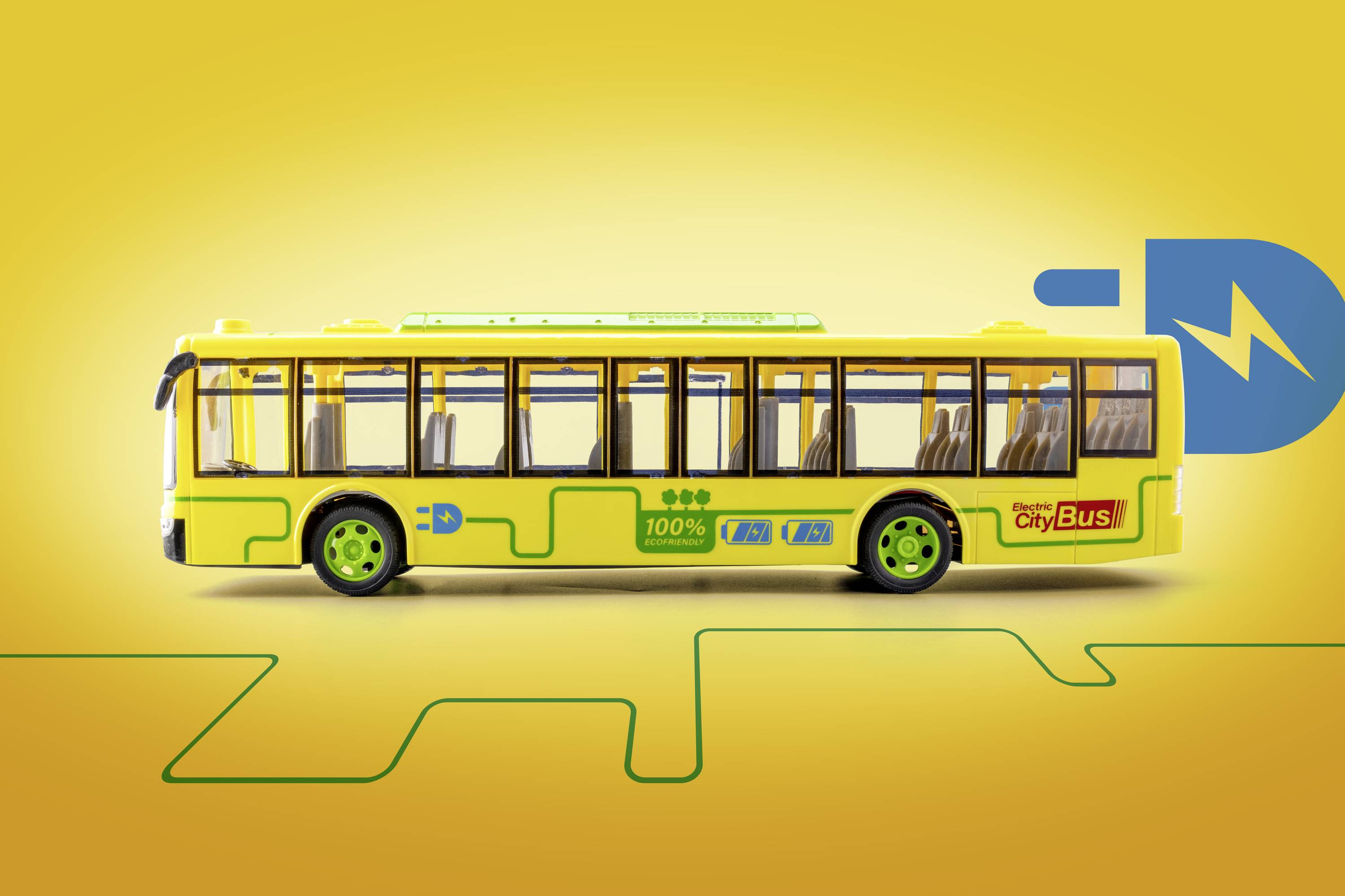 Żółty autobus modelowy z zielonymi kołami stoi na żółtym tle. Na autobusie widnieją napisy takie jak '100%' i 'City Bus'.
