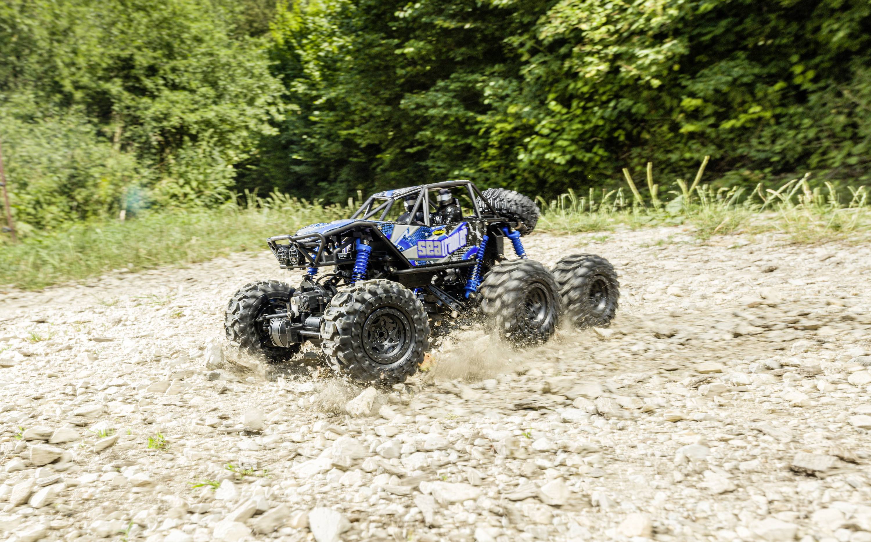 Zdalnie sterowany samochód szybko pędzi po kamienistej ścieżce w zielonej, leśnej scenerii.