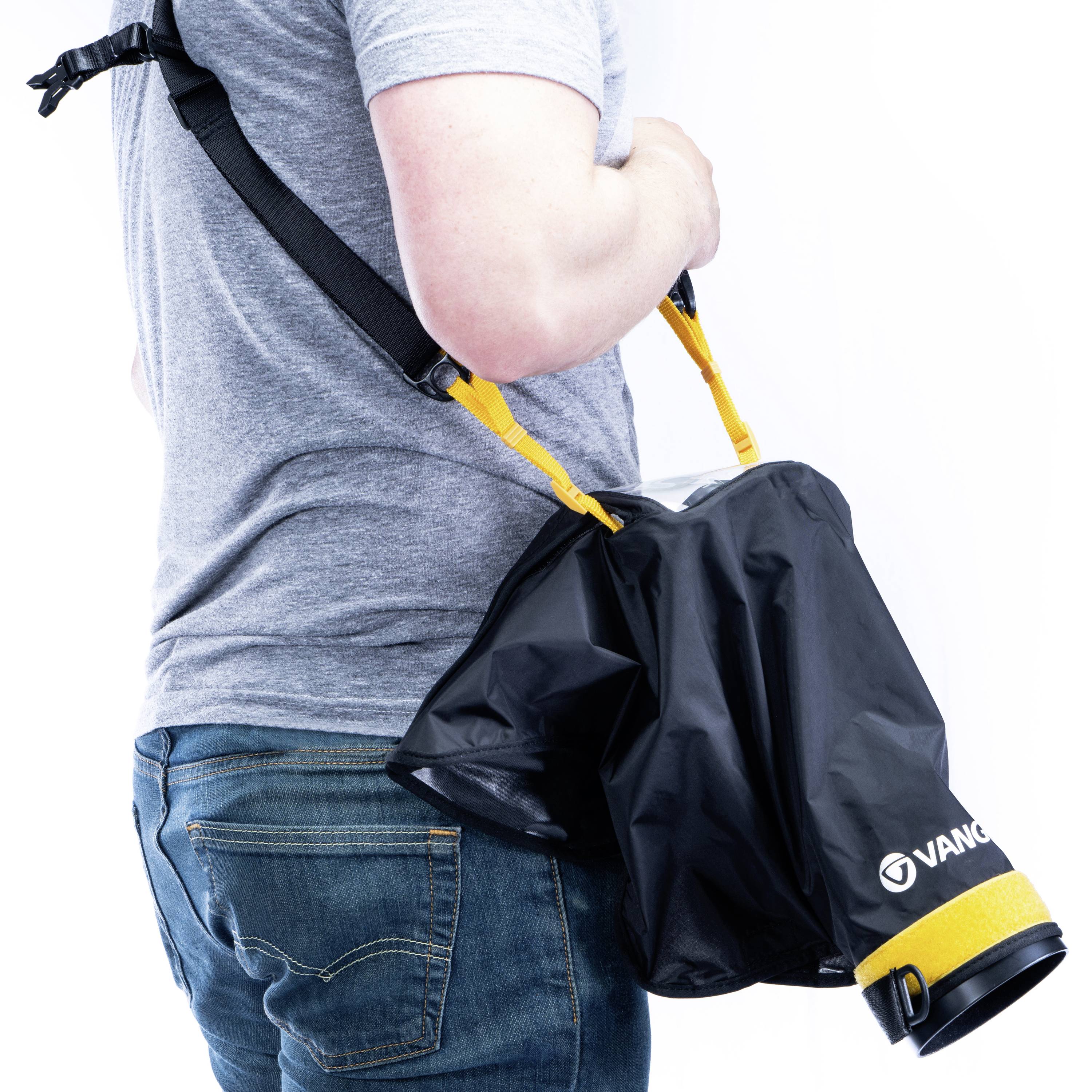 Osoba nosi czarną wodoodporną płaszczkę z paskiem przewieszonym przez ramię.