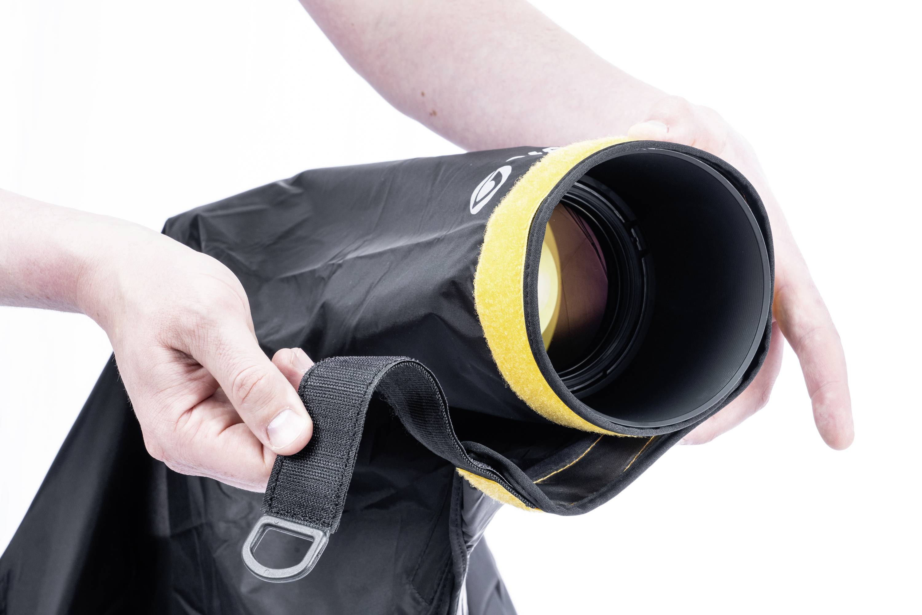 Osoba trzyma czarną torbę z żółtą krawędzią i uchwytem. Torba wydaje się być pokrowcem ochronnym dla jakiegoś przedmiotu.