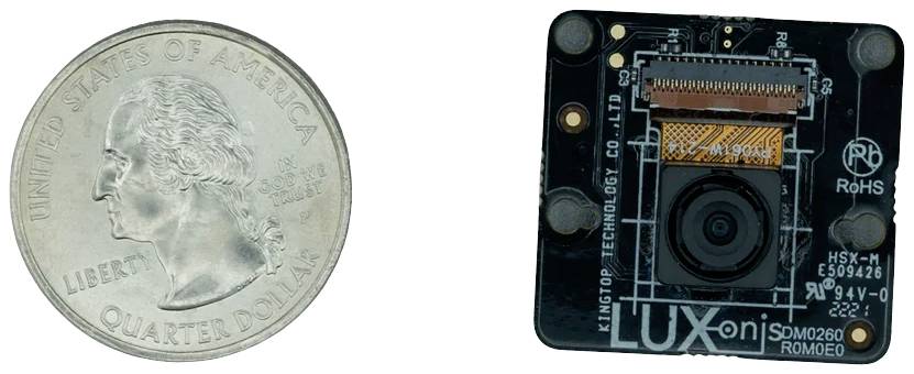 Moneta amerykańskiego dolara ćwiartkowego obok małego modułu kamery. Pokazuje rozmiar modułu w porównaniu do monety.