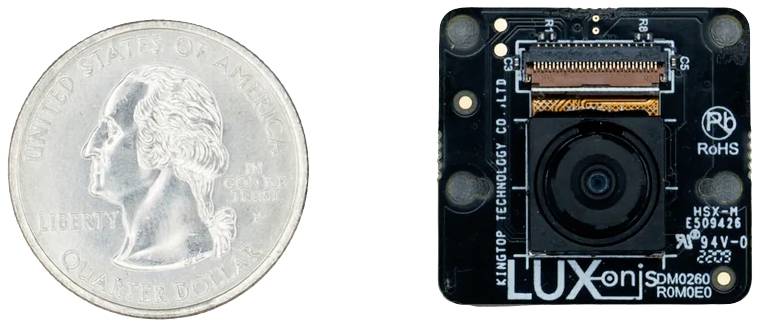 Moneta 25-centowa USA umieszczona obok małej kamery firmy LUX-ON, model DM0260, ilustruje porównanie rozmiarów.