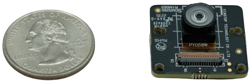 Amerykańska moneta o wartości dwudziestu pięciu centów leży po lewej stronie małego modułu kamery na białej powierzchni.