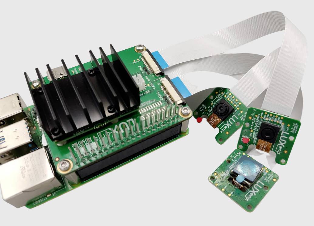 Zielona płytka rozwojowa z radiatorem jest podłączona do trzech małych modułów kamerowych. Programiści używają jej do projektów związanych z przetwarzaniem obrazu lub wizją komputerową.