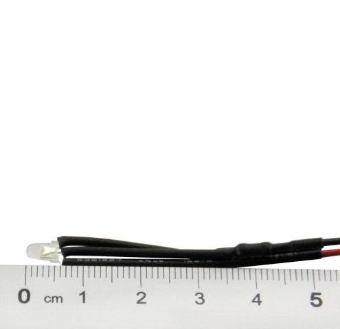 Mała dioda LED jest przymocowana do dwóch czarnych przewodów, które leżą obok linijki wskazującej centymetry i cale.