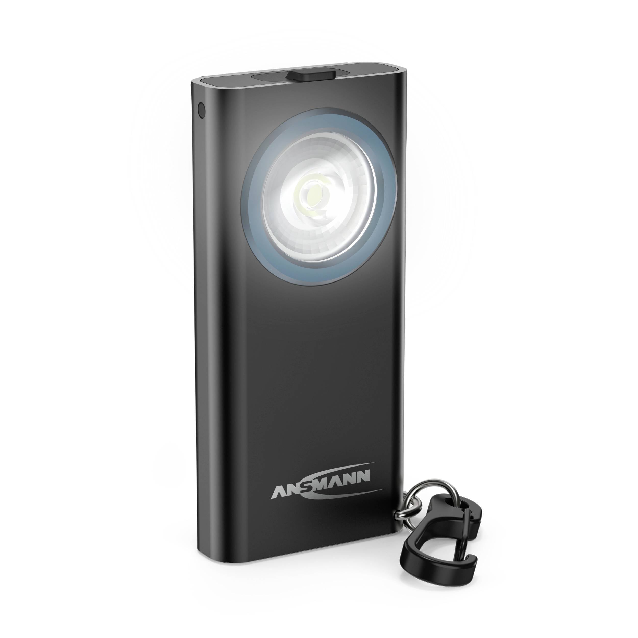 Czarna latarka z okrągłą głowicą świecącą, niebieskim pierścieniem wokół soczewki i małym karabińczykiem na obudowie.