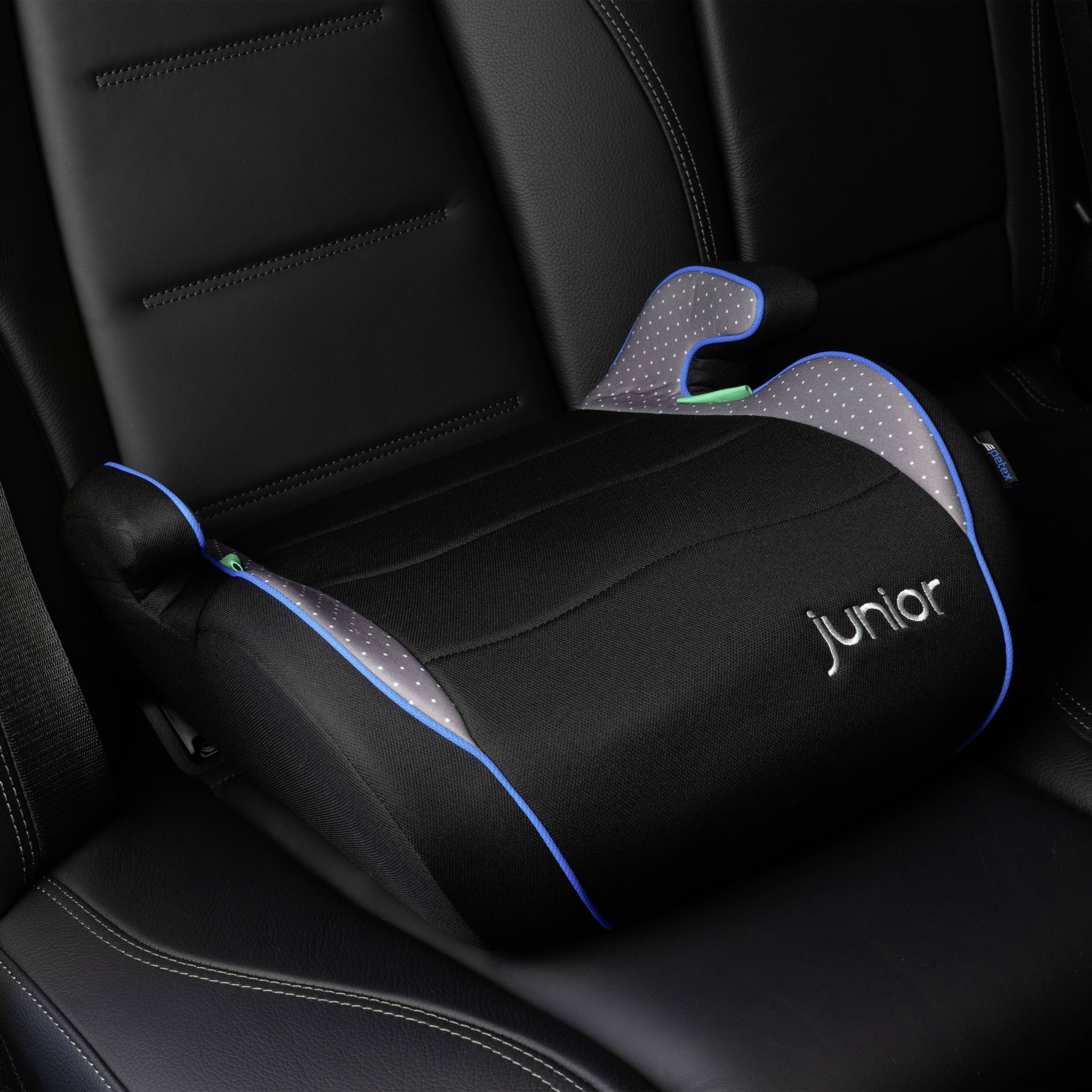 Czarna podwyższka dla dziecka z niebieskimi akcentami i napisem 'junior' leży na siedzeniu samochodowym.
