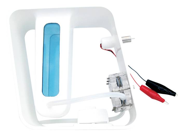 Miniaturowy model elektrowni wodnej z zbiornikiem wody, turbiną oraz czerwonymi i czarnymi zaciskami krokodylkowymi do eksperymentów z wytwarzaniem energii elektrycznej.