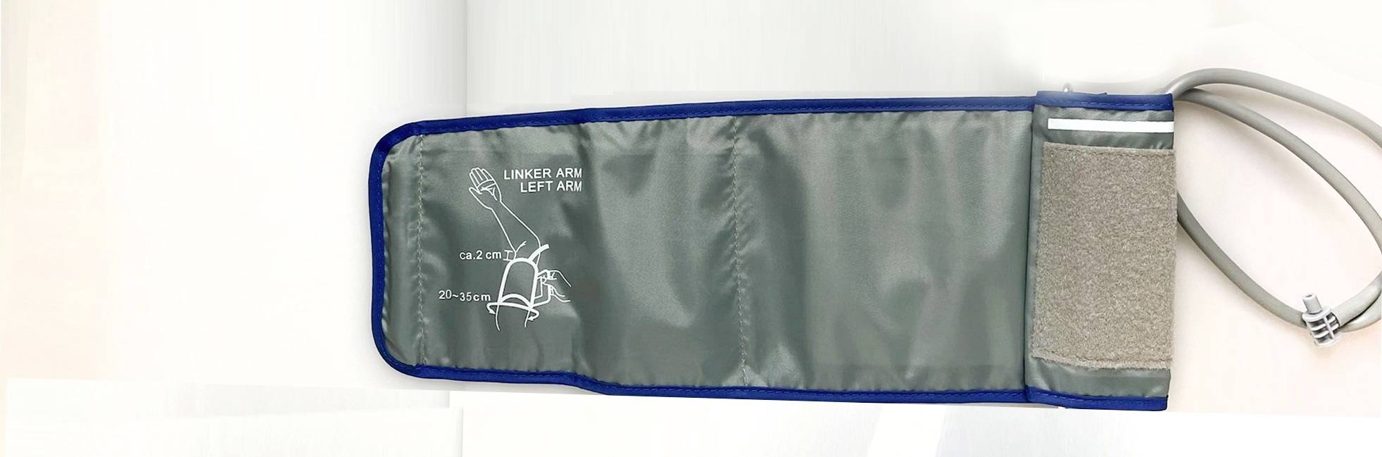 Mankiet do pomiaru ciśnienia krwi na lewą rękę z grafiką przedstawiającą prawidłowe umiejscowienie, wykonany z szarego materiału z niebieską obwódką.