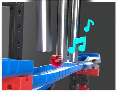 Piłka toczy się wzdłuż niebieskiej szyny i napotyka metalowe rury, które wydają dźwięki. Obok unoszą się nuty muzyczne.