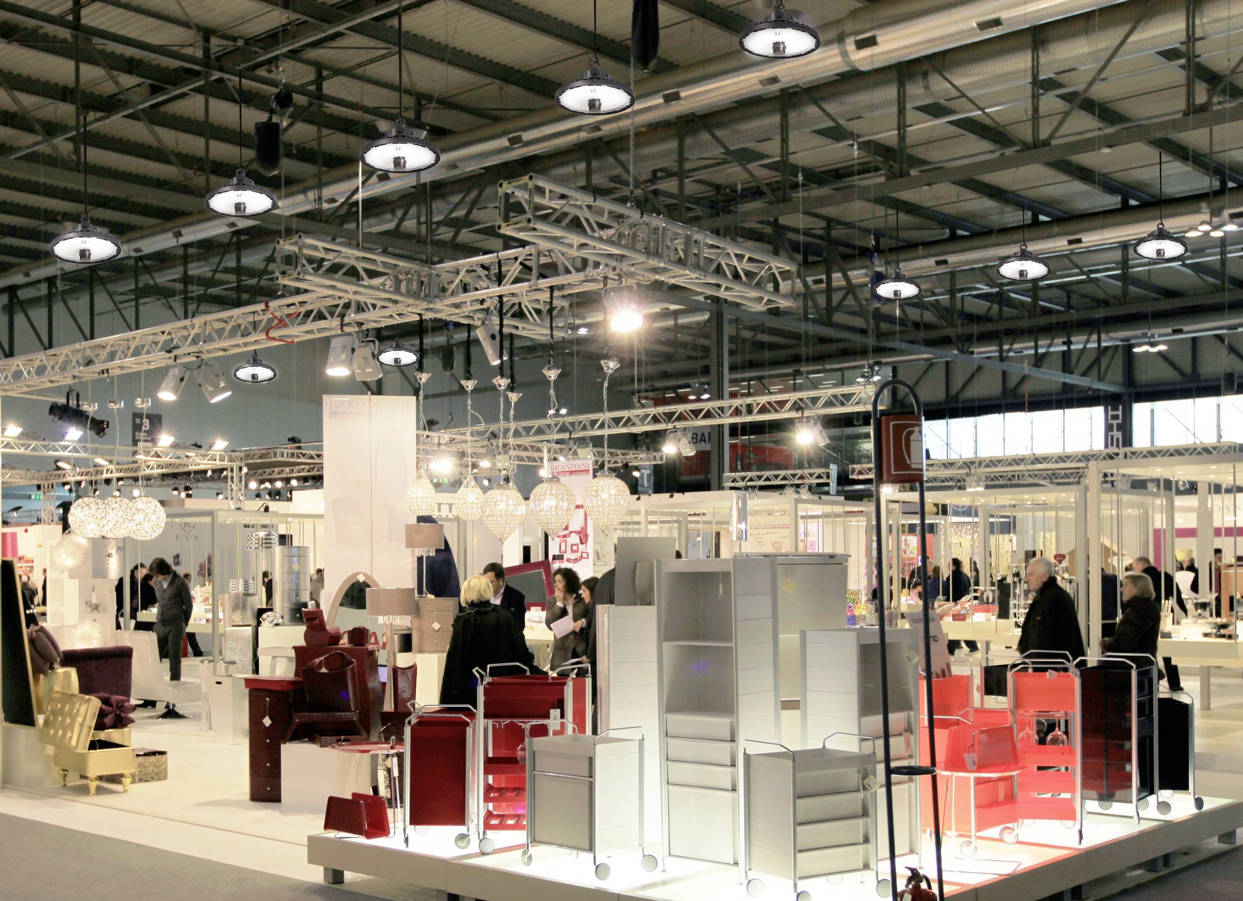 Hala wystawowa z odwiedzającymi oglądającymi stoiska z meblami i elementami wyposażenia wnętrz. Jasne oświetlenie i nowoczesne ekspozycje.