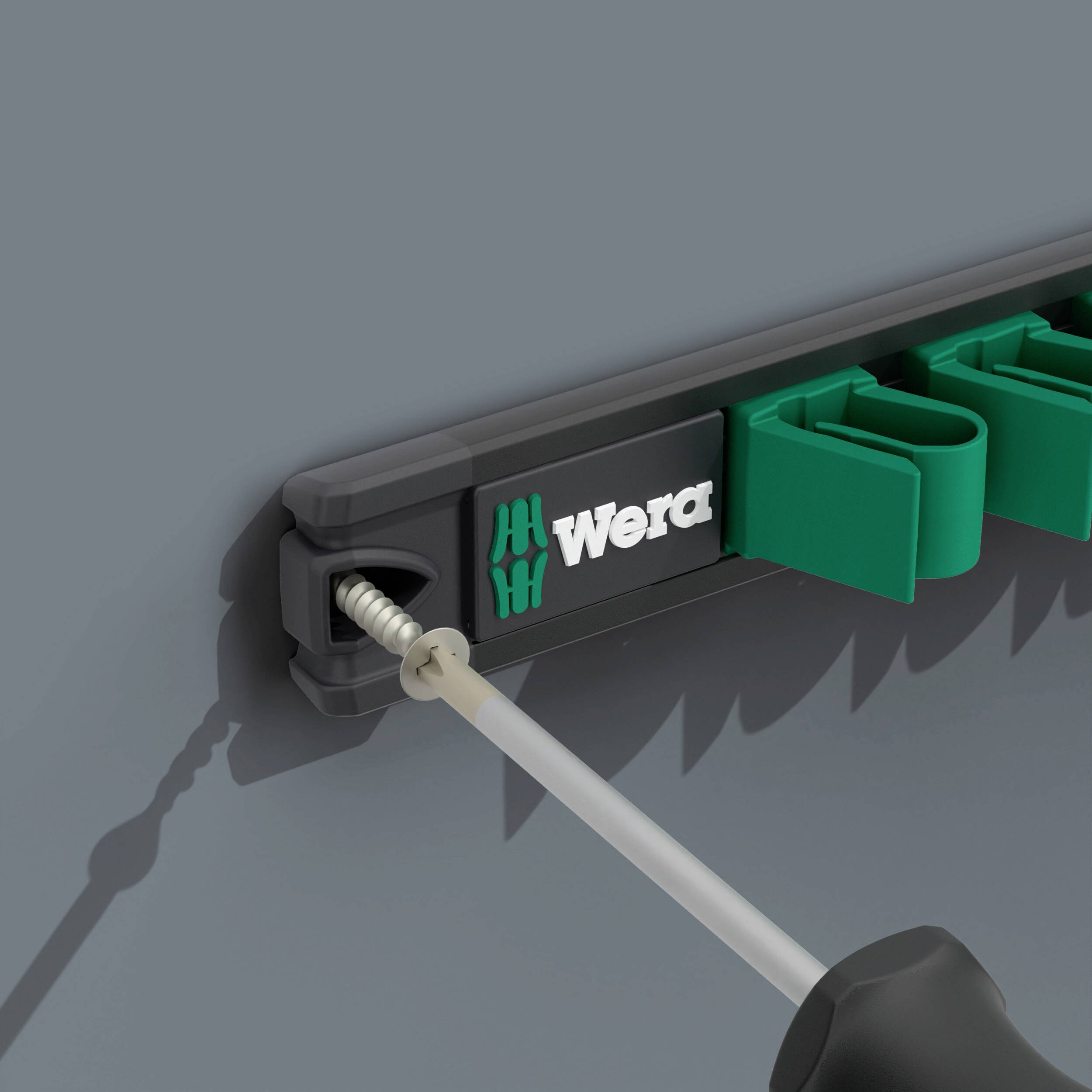 Wkrętak zostaje wsunięty w uchwyt zamocowany na ścianie. Uchwyt nosi logo marki 'Wera'.