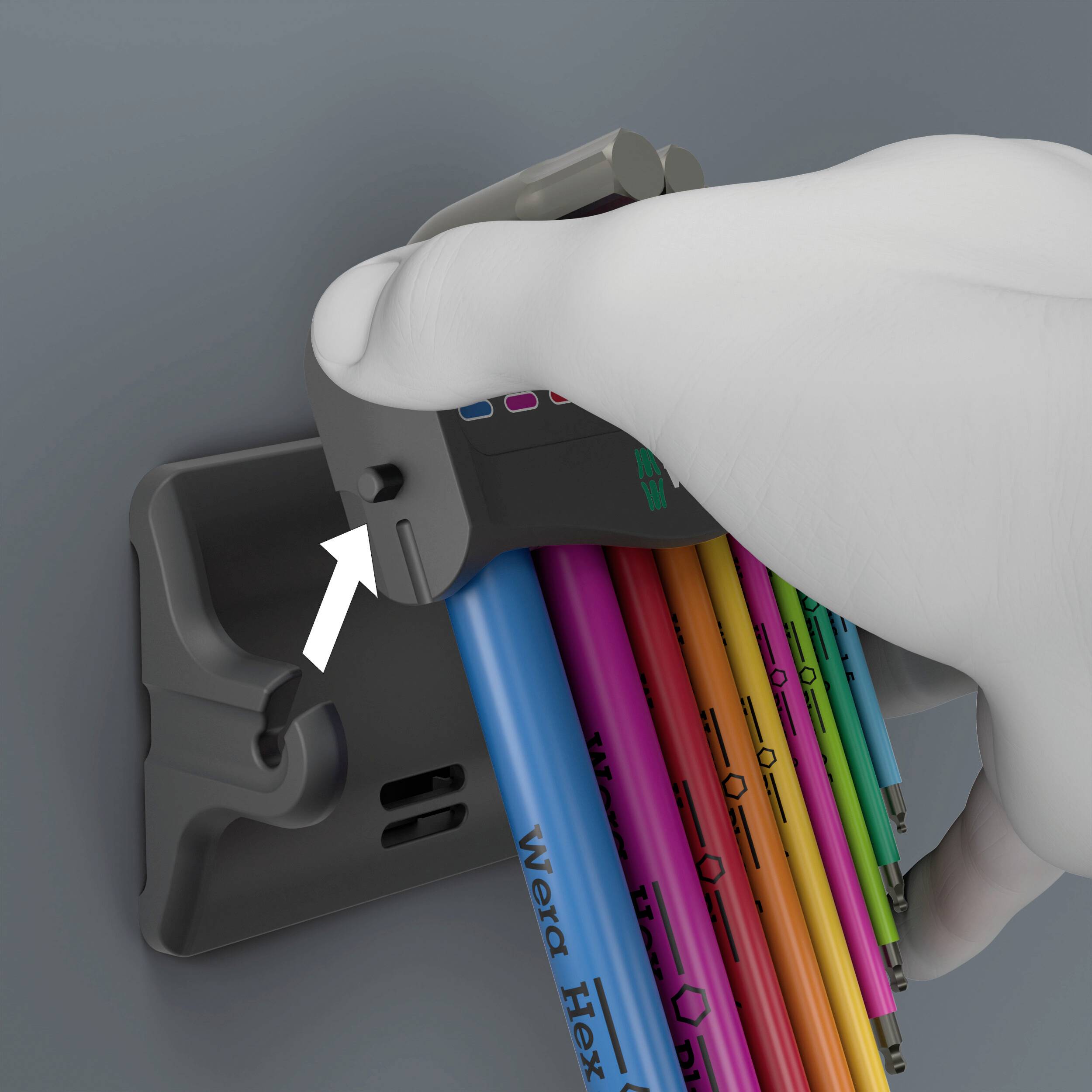 Ręka wyjmuje kolorowy klucz sześciokątny z uchwytu ściennego. Klucz jest oznaczony napisem 'Wera Hex'.