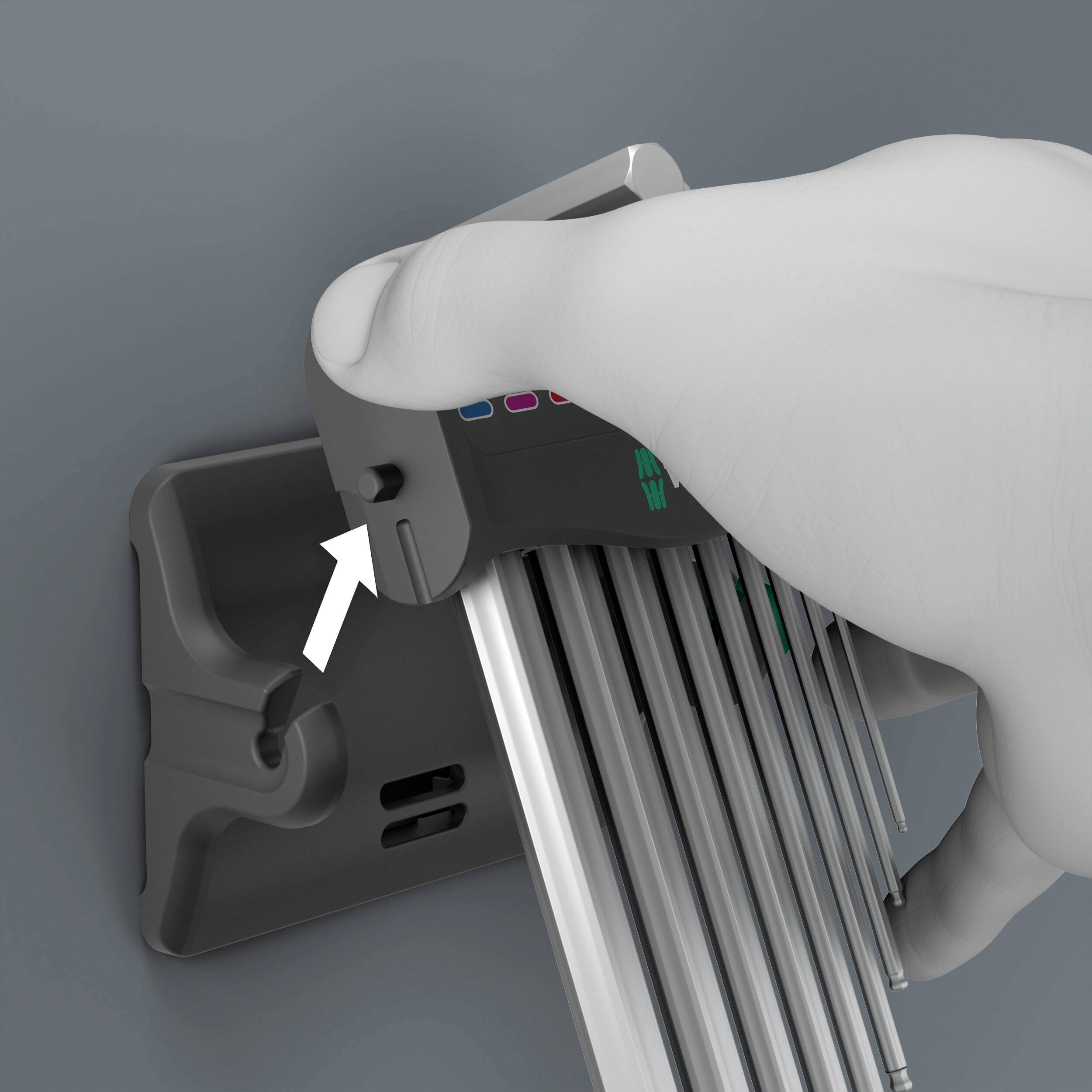 Dłoń naciska przycisk na urządzeniu z długimi, równoległymi prętami. Strzałka wskazuje miejsce naciśnięcia.