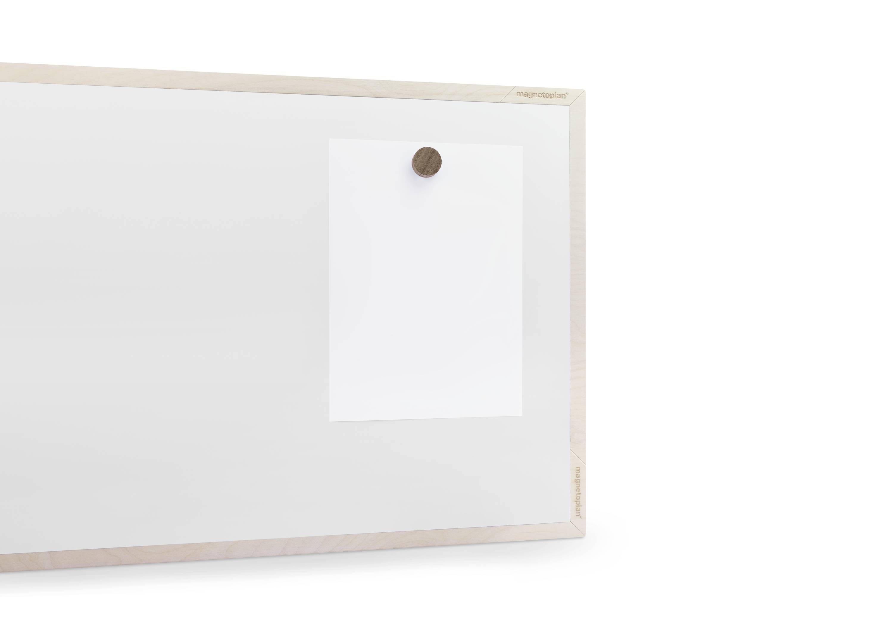Biała tablica magnetyczna z drewnianą ramą, na której przytwierdzony jest biały arkusz papieru za pomocą okrągłego, brązowego magnesu.