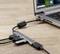 Laptop jest podłączony do kilku urządzeń USB za pośrednictwem rozgałęziacza USB. Hub leży na drewnianym stole, laptop jest częściowo widoczny.