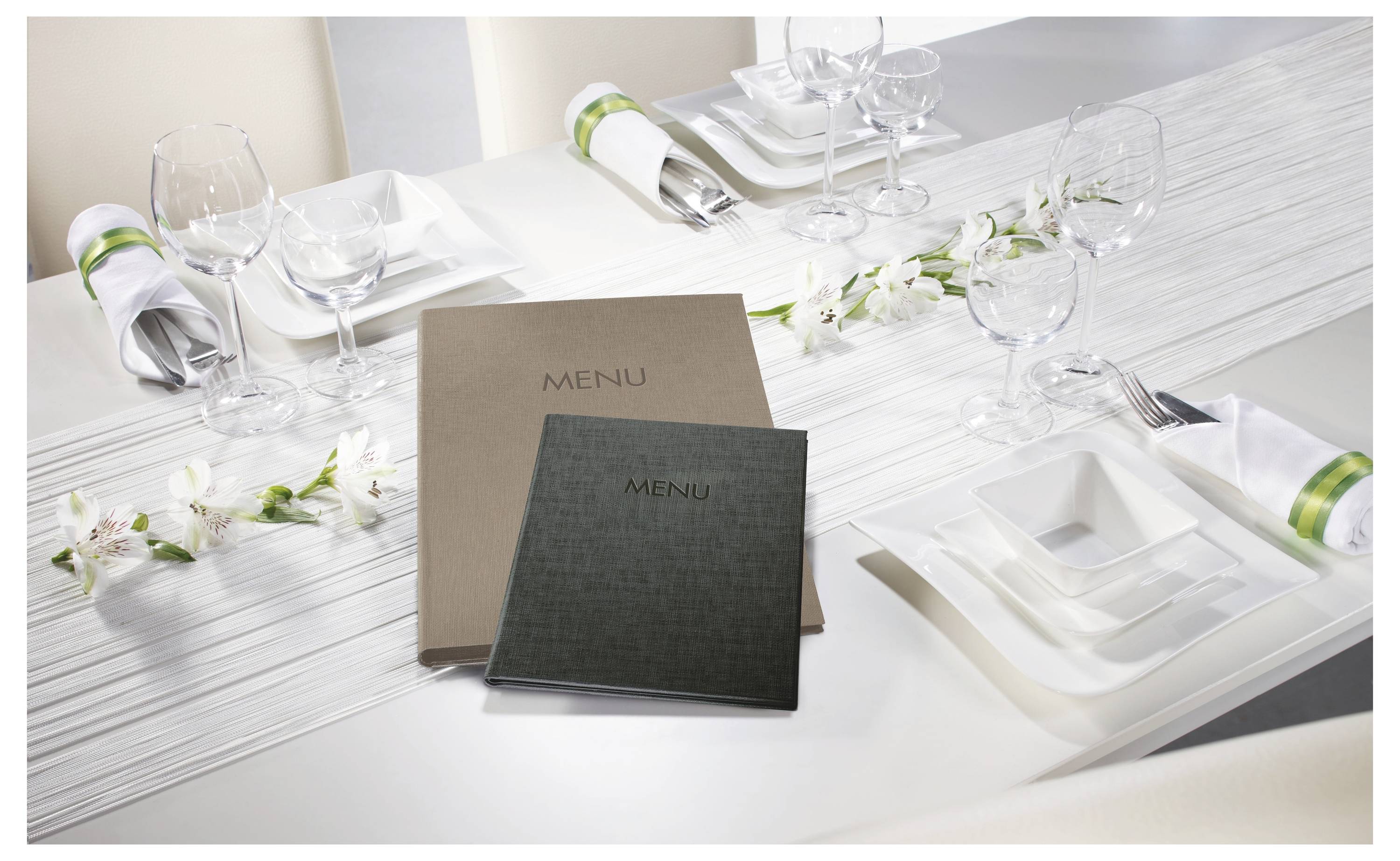 Formalne ustawienie stołu na białym blacie ze serwisem, złożonymi serwetkami, kieliszkami do wina i białymi dekoracjami kwiatowymi.