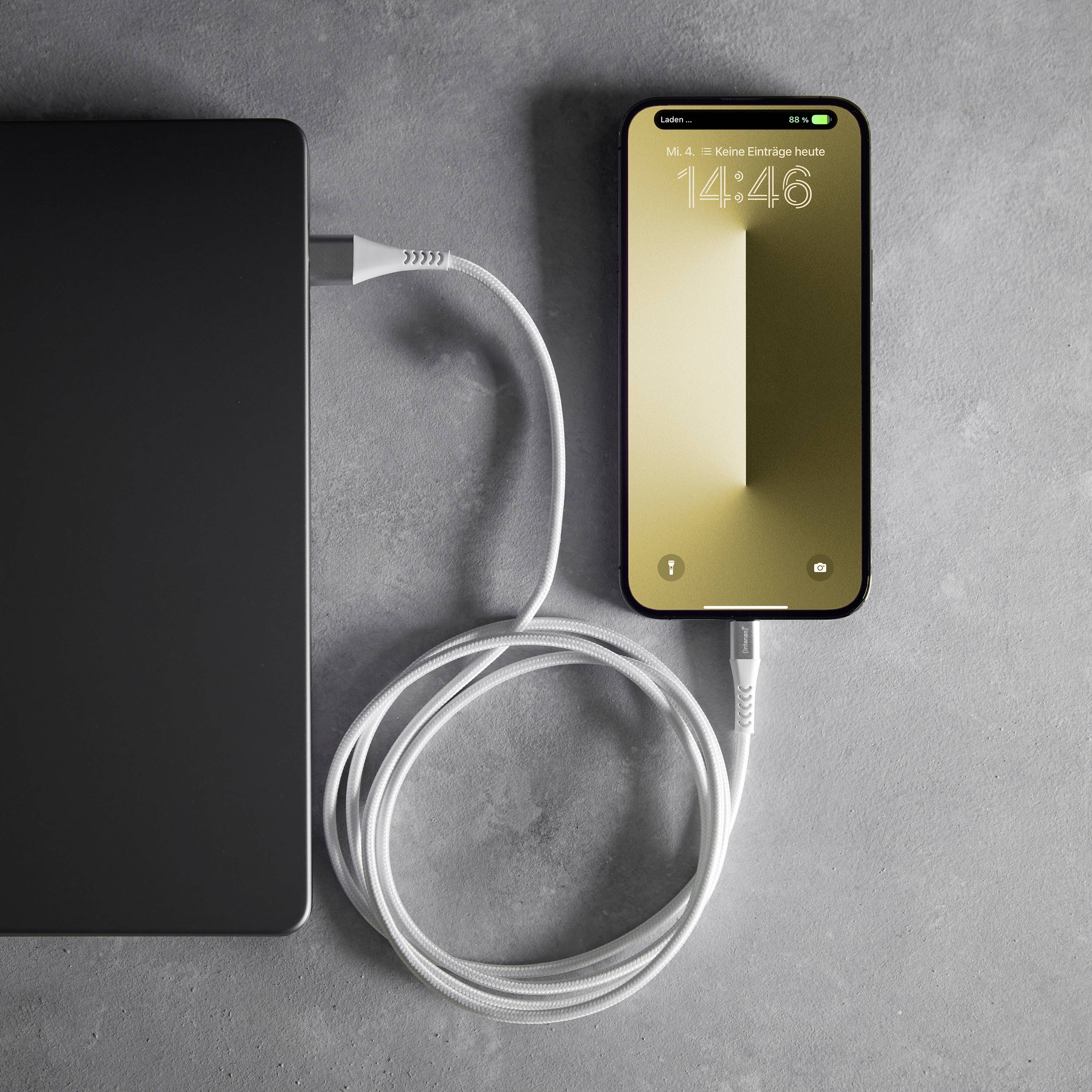 Smartfon ładuje się przez podłączony kabel z czarnego powerbanku na szarym tle.