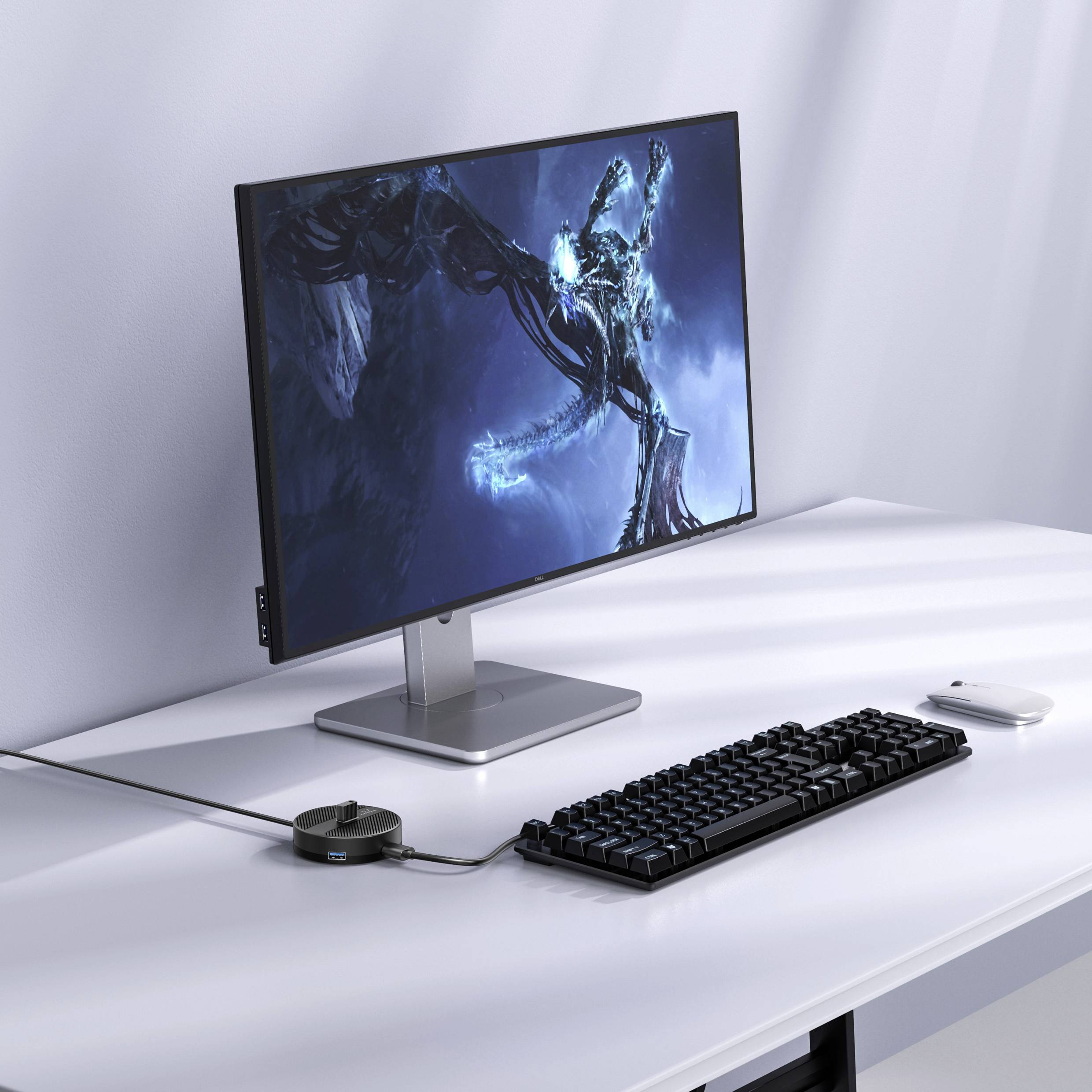 Stanowisko komputerowe z płaskim monitorem, klawiaturą i myszą na białym biurku. Ekran wyświetla niebieski, futurystyczny projekt.