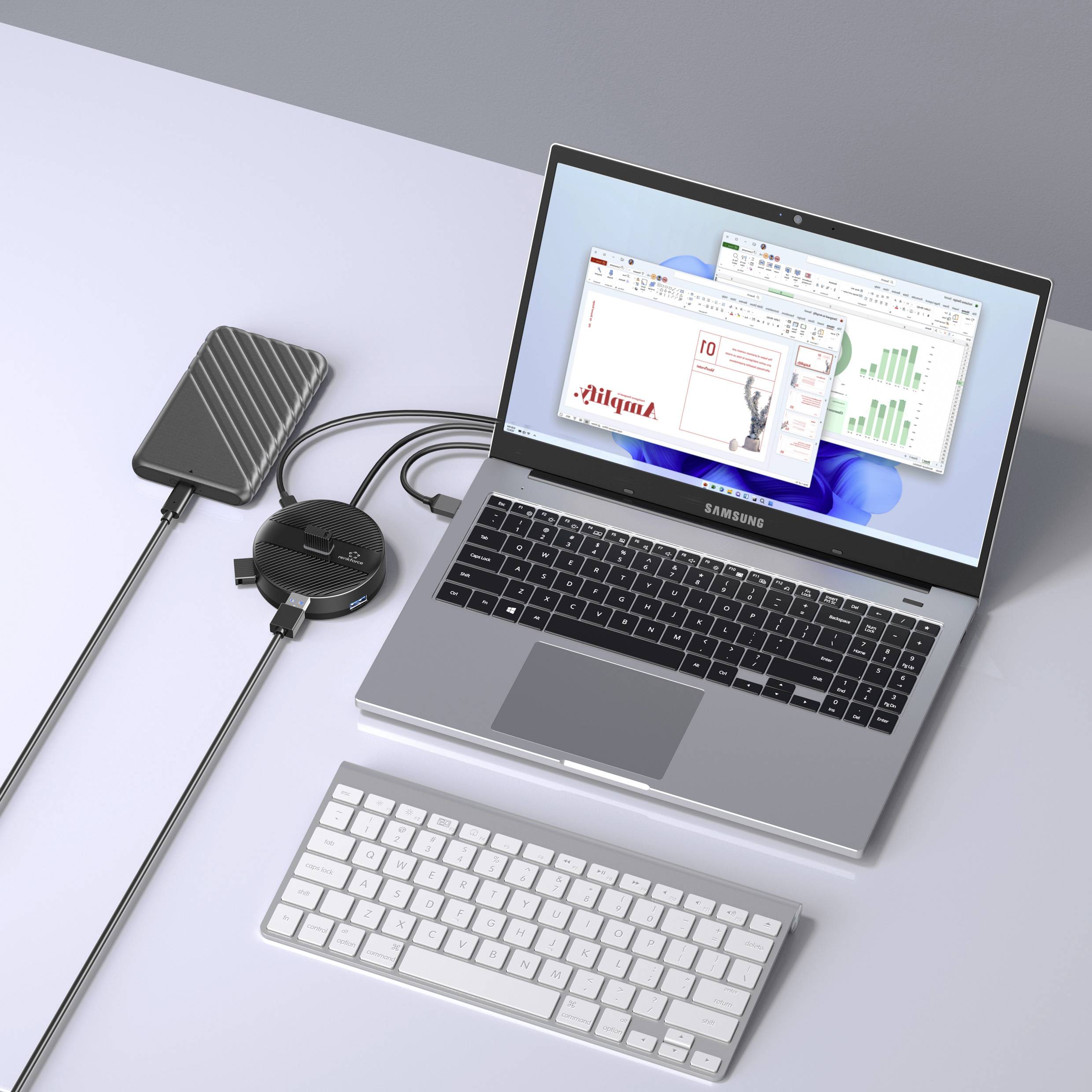 Otwarty laptop wyświetla wykresy biznesowe na ekranie. Obok niego leżą zewnętrzny dysk twardy, hub USB i klawiatura.