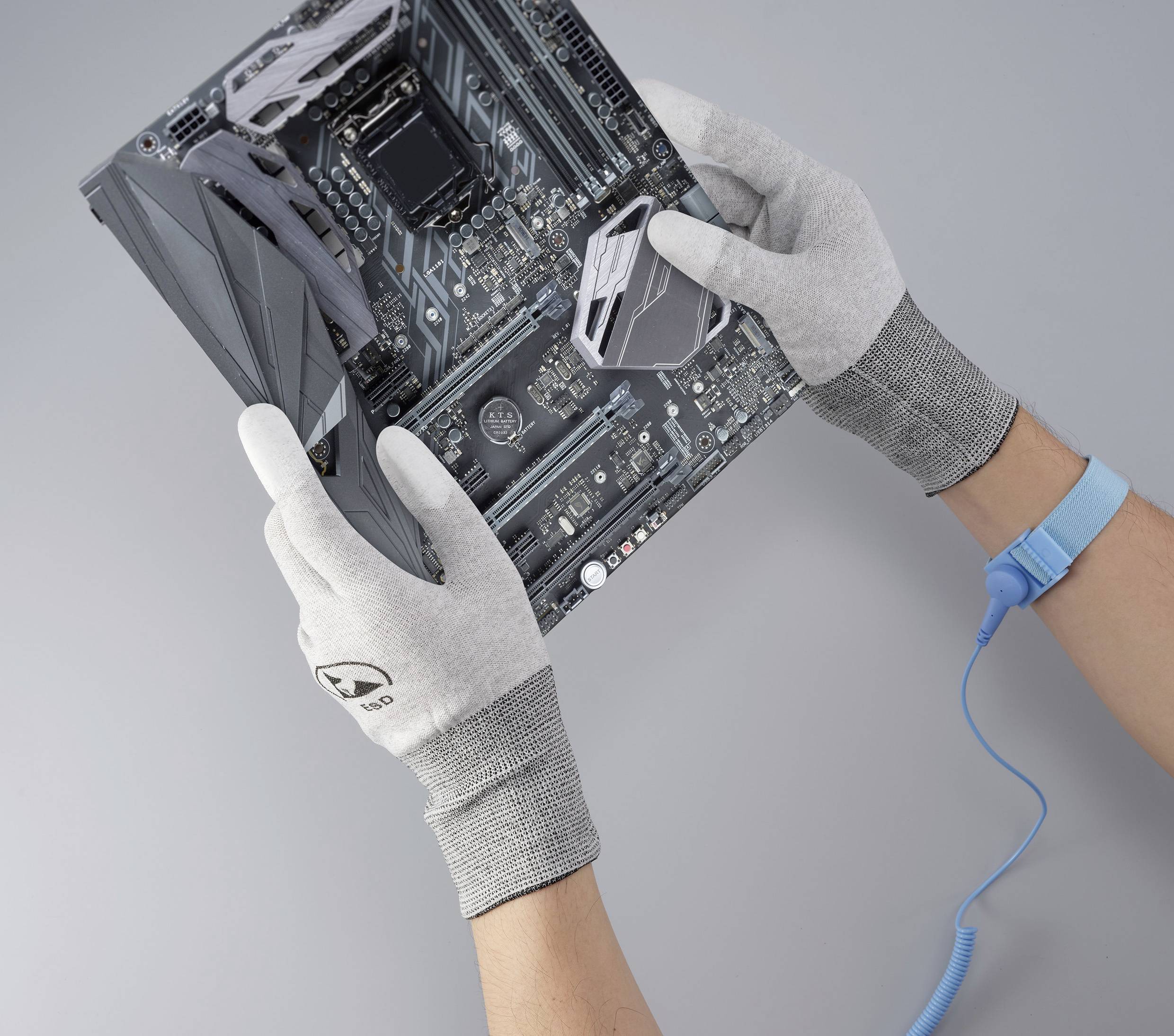 Ręce w szarych rękawiczkach trzymają płytkę głównej płyty komputerowej.