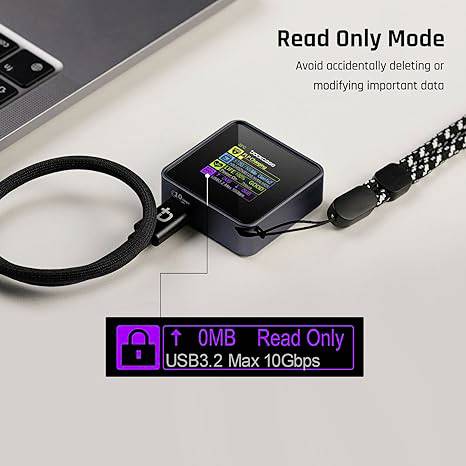 Mała pamięć przenośna z napisem 'Tryb tylko do odczytu' i 'USB3.2 Maks. 10 Gb/s', leży obok laptopa.