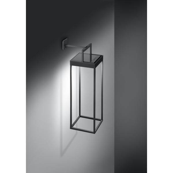 Nowoczesna lampa ścienna z metalu z prostokątną, otwartą ramą, zamontowana na szarej ścianie, świecąca w dół.