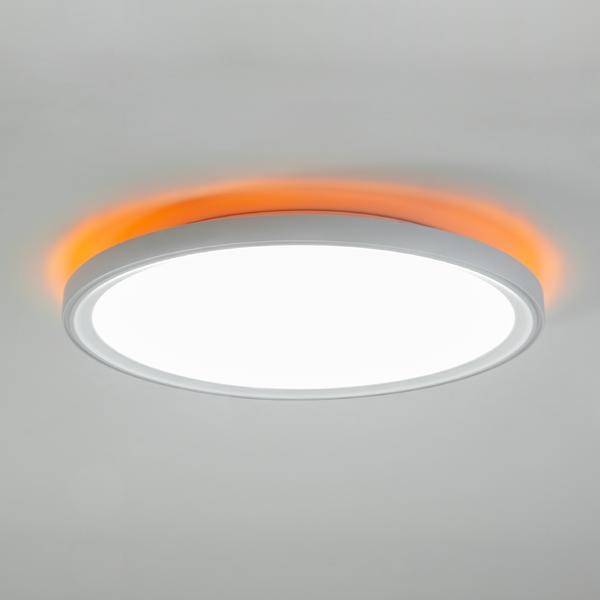 Okrągła lampa sufitowa z białym światłem, otoczona pomarańczową obwódką świetlną; nowoczesny i minimalistyczny design.