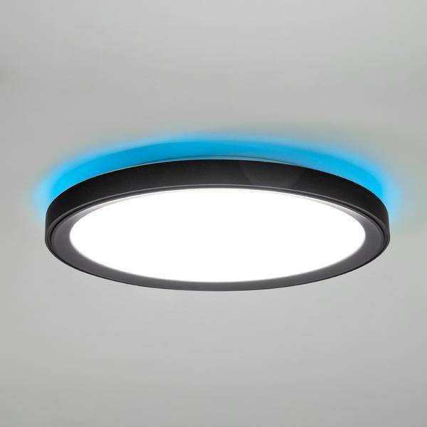 Okrągła lampa sufitowa LED z czarną ramką i niebieskim podświetleniem, jasno świecąca na szarym suficie.