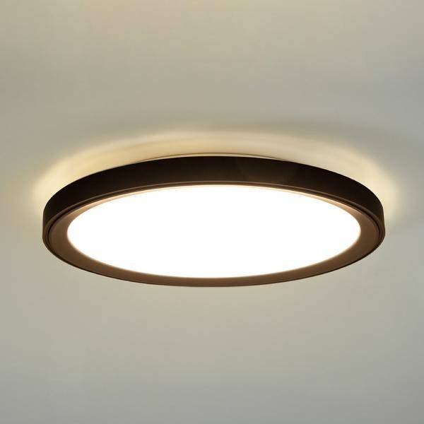 Okrągła, nowoczesna lampa sufitowa z ciepłym, białym światłem, zamocowana na prostym, jasnym suficie.