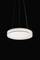 Lampa wisząca z okrągłym, białym kloszem na czarnym tle.