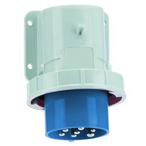 Niebieski wtyk CEE z obudową z tworzywa sztucznego z pięcioma stykami, zamontowany na białej ścianie, przeznaczony do podłączenia do przemysłowych źródeł zasilania.