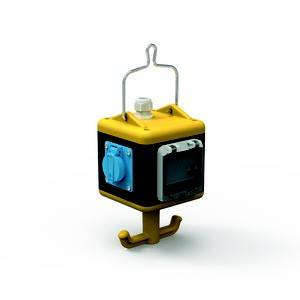 Żółty, sześcienny adapter z niebieskimi gniazdkami i haczykiem na dole, zawieszony na wieszaku druciaku.