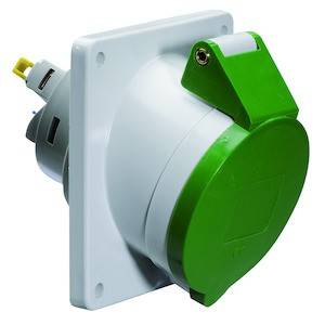 Zielony wtyk kątowy z ukośnym złączem kablowym, zamontowany na białej płycie. Standardowy element osprzętu elektrycznego.