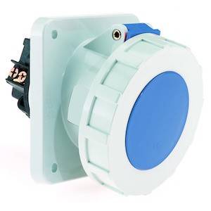 Przełącznik z niebieskim przyciskiem i białą obudową, odpowiedni do zastosowań przemysłowych, zamontowany na białej ścianie.