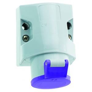 Gniazdo ścienne z niebieską pokrywą ochronną, odpowiednie do zastosowań przemysłowych, zainstalowane na białej ścianie.