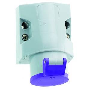 Przemysłowe gniazdo elektryczne z niebieskim kapturkiem ochronnym, zamontowane na płycie ściennej. Służy do podłączania urządzeń w środowiskach przemysłowych.