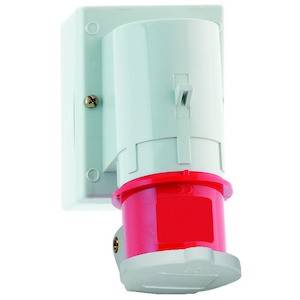 Przemysłowe gniazdo elektryczne z czerwoną obudową, zamontowane na białej płycie ściennej, typowo stosowane do podłączeń wysokoprądowych w budynkach komercyjnych.