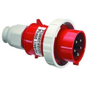 Obraz przedstawia czerwony, przemysłowy wtyk fazowy z pięcioma metalowymi stykami, dostosowany do połączeń elektrycznych.