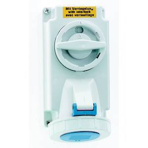 Biały przemysłowy przełącznik obrotowy z blokadą i niebieskim gniazdem, zamontowany na białej płycie. Naklejka bezpieczeństwa u góry.