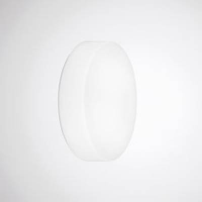 Okrągła, prosta, biała lampa zamontowana na białej ścianie. Lampa charakteryzuje się minimalistycznym designem.
