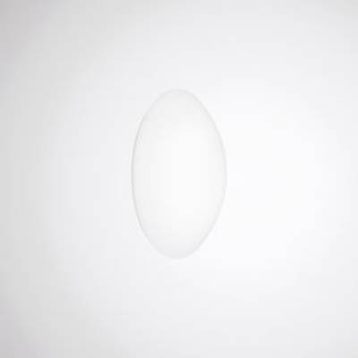 Owalny, centralny cień na białej ścianie; minimalistyczny design kładący nacisk na prostą formę i efekt świetlny.