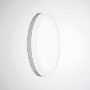 Owalna, biała lampa ścienna równomiernie oświetla minimalistycznie urządzone pomieszczenie.