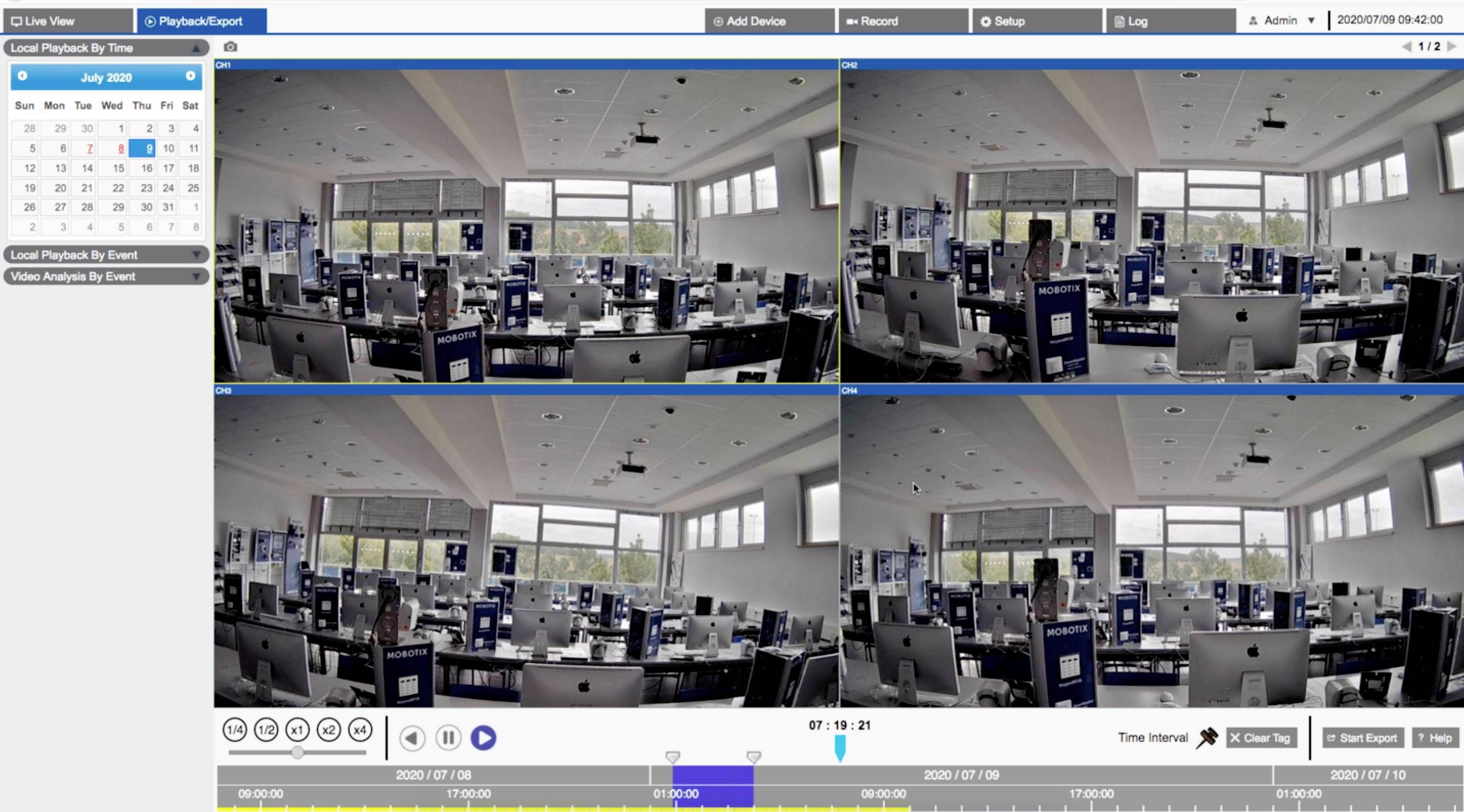Zdjęcia z monitoringu pustego biura z wieloma monitorami i dużymi oknami. Widok jest podzielony na cztery sekcje.