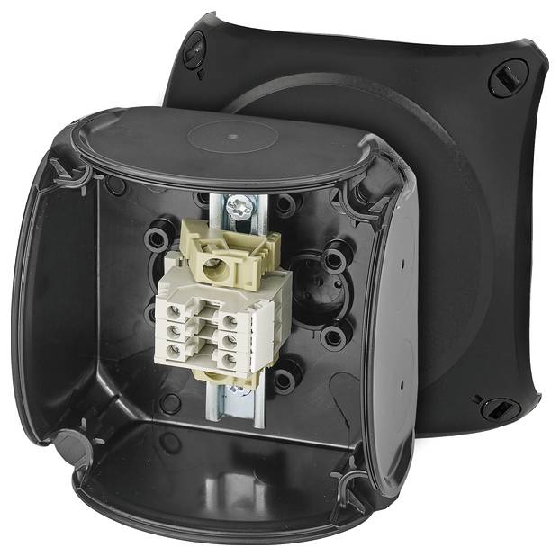 Otwarty, pusty plastikowy puszka przyłączeniowa z widocznymi wejściami kablowymi oraz wewnętrznym elementem przyłączeniowym w metalowym uchwycie.