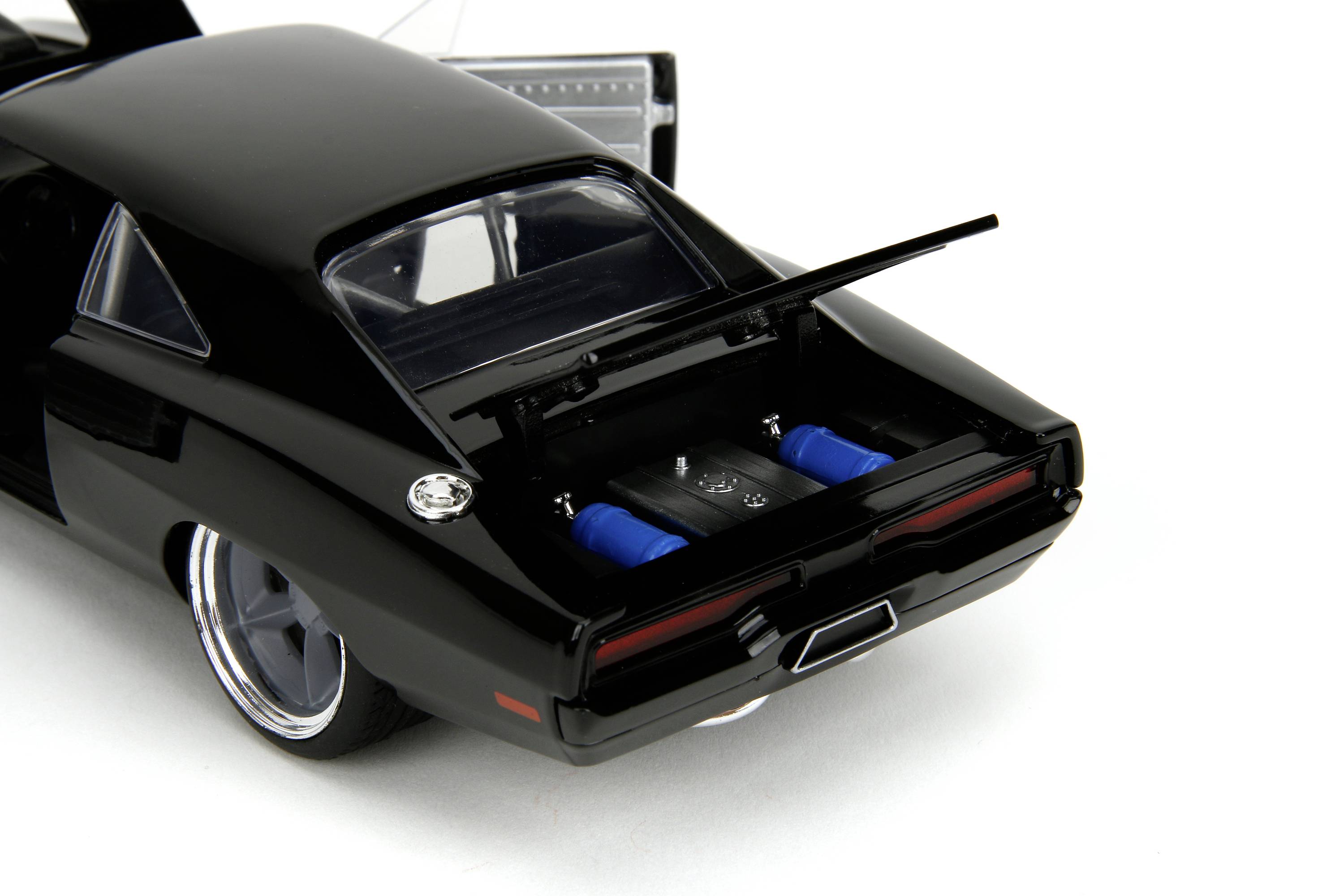 Czarny model samochodu z otwartą tylną klapą, w której widoczne są dwa niebieskie cylindry. Drzwi samochodu również są otwarte.