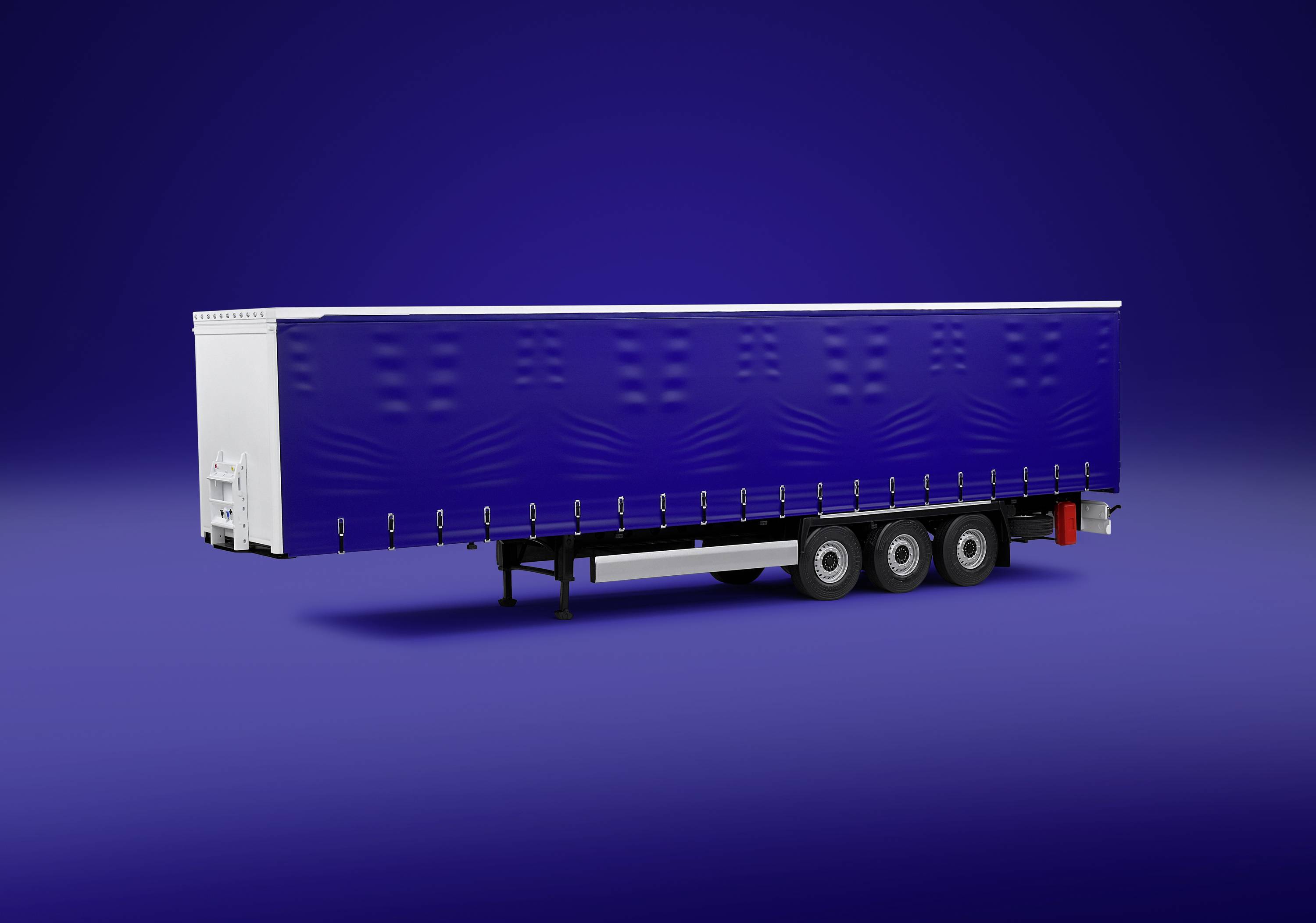 Niebieski przyczepa ciężarówki z białymi elementami stoi na jednobarwnym niebieskim tle.