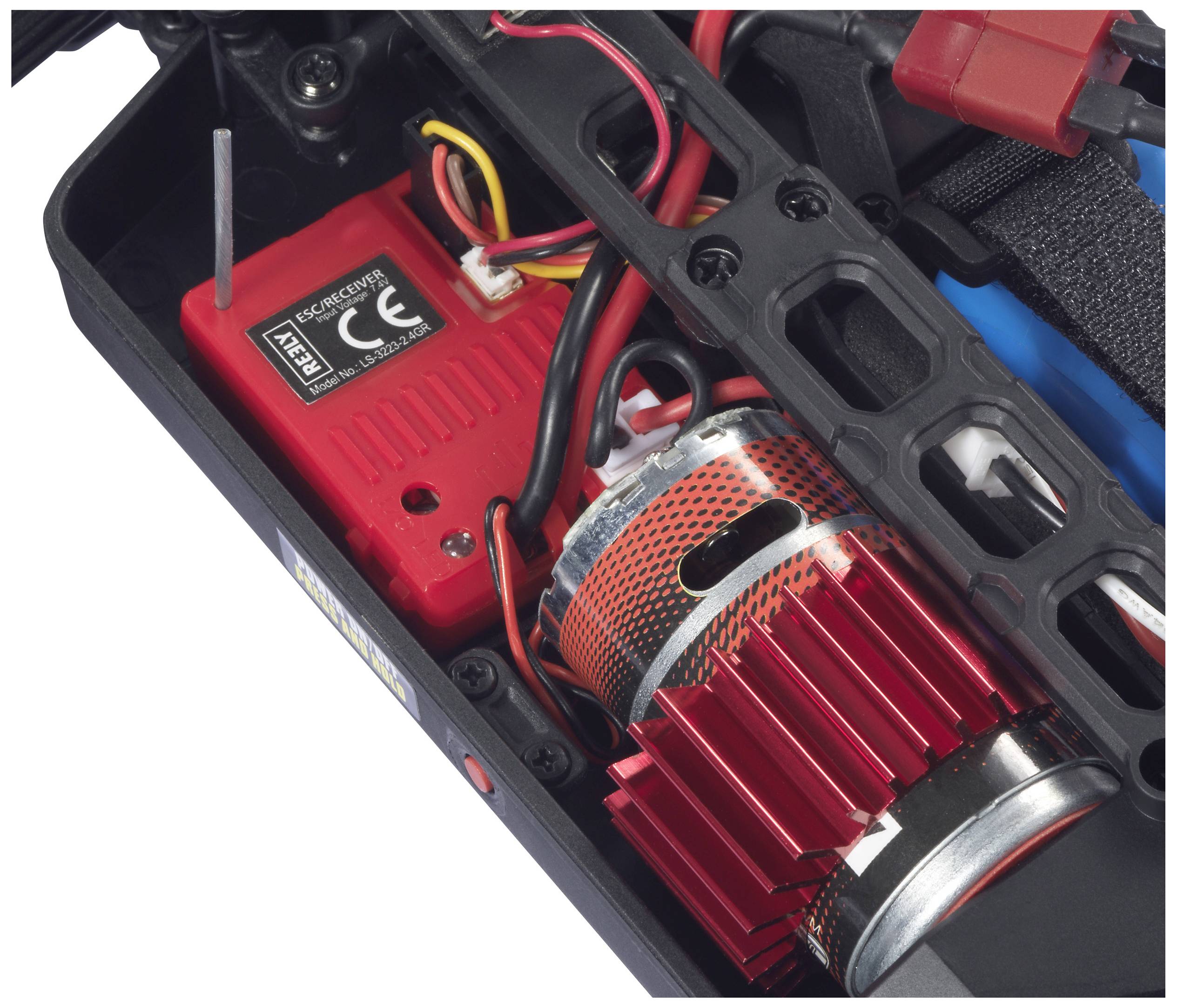 Czerwony silnik elektryczny z żebrami chłodzącymi w samochodzie zdalnie sterowanym, otoczony przewodami i urządzeniem sterującym, widoczny od wewnątrz.