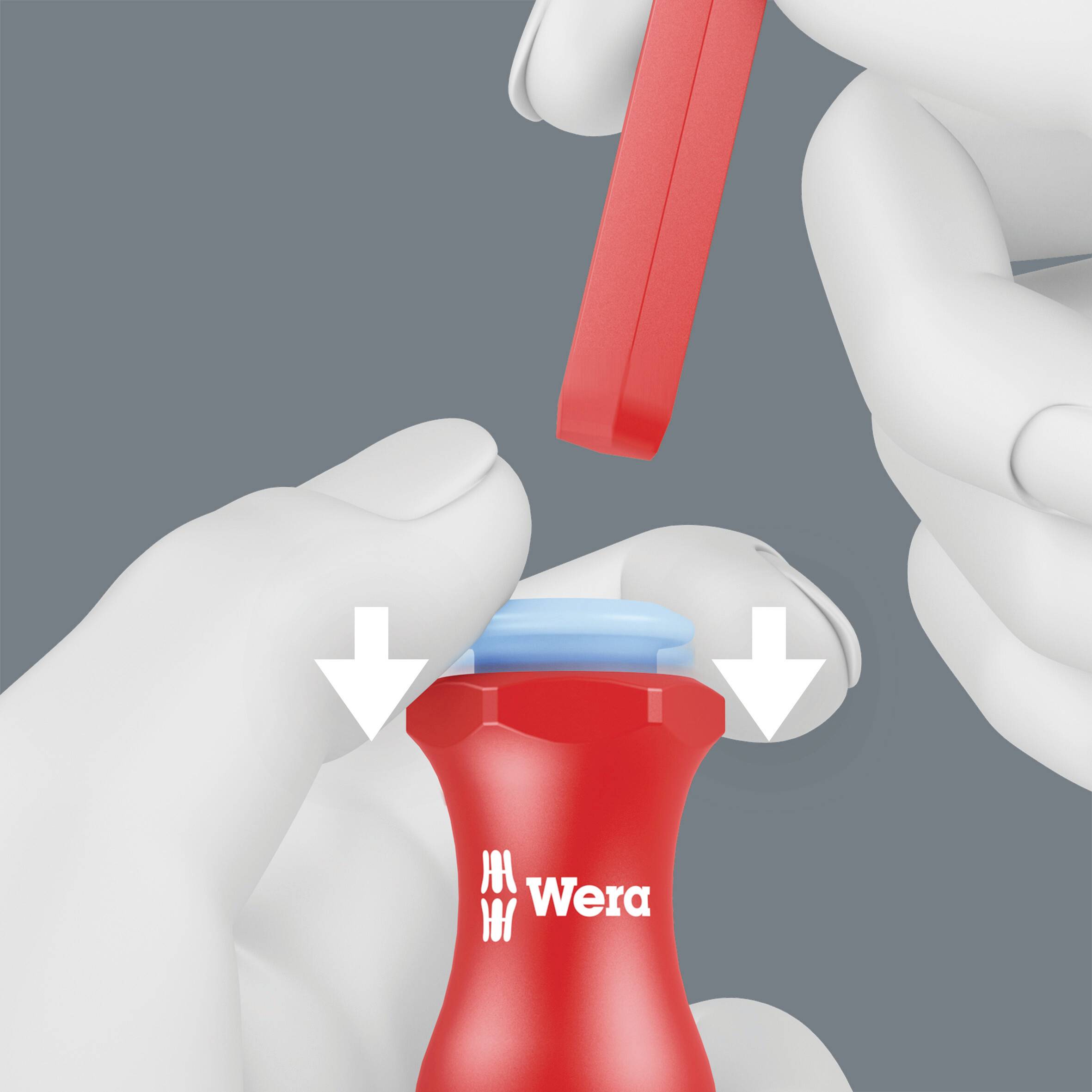 Dwie ręce obracają wkrętak Wera z czerwonym uchwytem. Ilustracja przedstawia kierunek wkręcania.